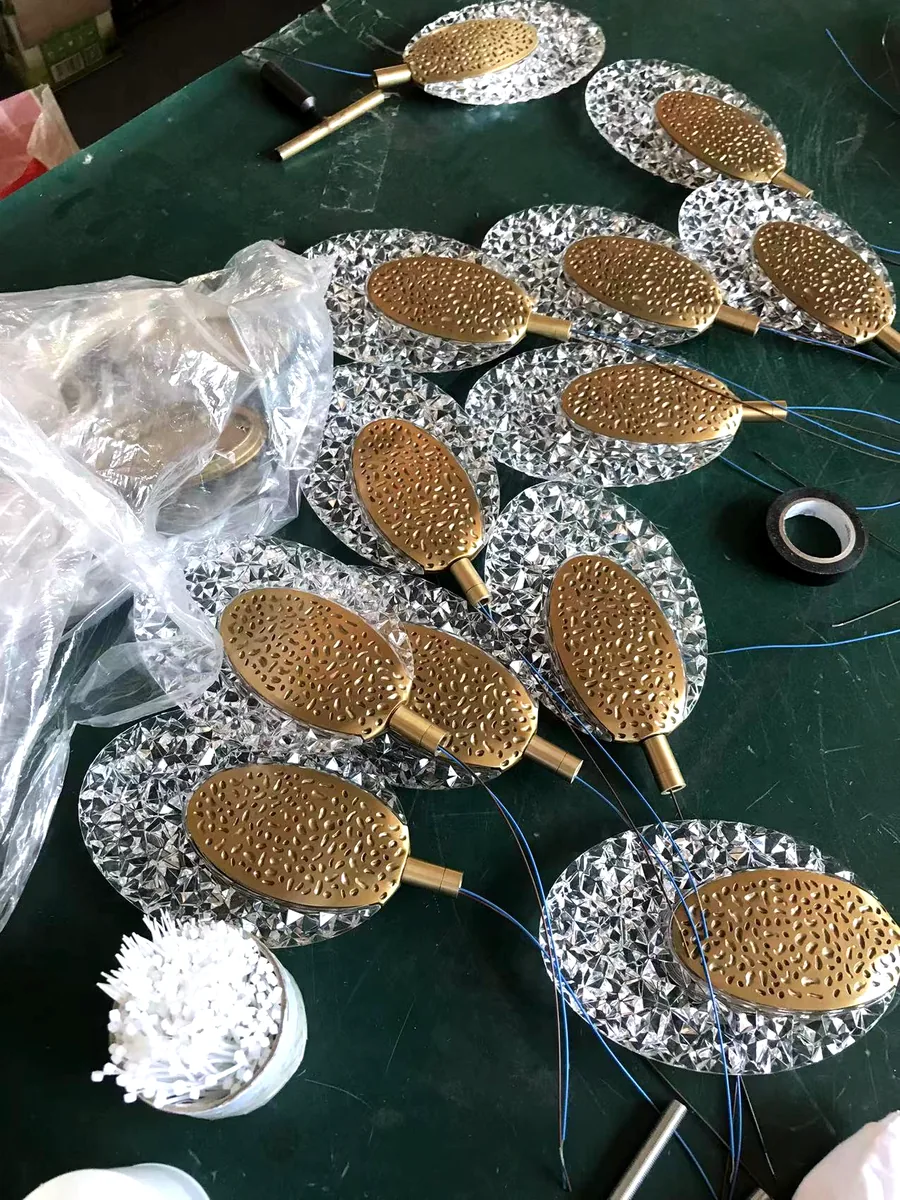 Crystal leaf components with perforated brass cores laid out for batch assembly